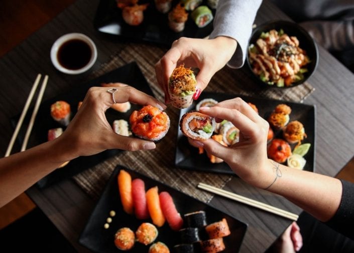 Three persons sharing plates of sushis